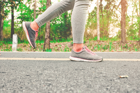 Ready for a sprint. Runner athlete standing on road towards sun. Concept of new start, travel, freedom etc. Close up cropped low angle photo of shoe of athlete.の写真素材
