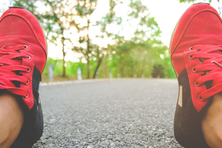 Woman Sitting On Road ready for a sprint. recreational running, Concept of new start, travel, freedom etc. Close up cropped low angle photo of shoe of athlete.の写真素材