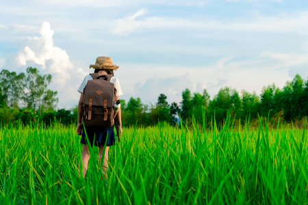 A happy girl enjoying nature in meadow. Outstretched arms, breathing fresh air with a cloudy blue sky in the background - concept of clean atmosphere.の写真素材