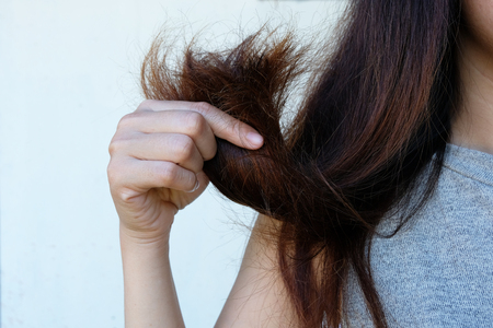 Sad Young Woman With Long Hair In Hand ,Hair Damage, Health And Beauty Concept.の写真素材