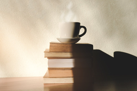 Stack old books with a cup of freshly coffee on wooden table in sunlight morning, Start up concept.の写真素材