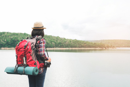 Hipster asian young girl with backpack enjoying sunset on peak mountain. Travel Lifestyle adventure concept vacations into the wild.の写真素材