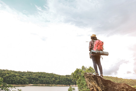 Hipster asian young girl with backpack enjoying sunset on peak mountain. Travel Lifestyle adventure concept vacations into the wild.の写真素材