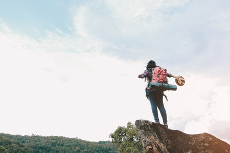 Hipster asian young girl with backpack enjoying sunset on peak mountain. Travel Lifestyle adventure concept vacations into the wild.の写真素材