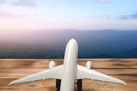 Mountain landscape with a view of the forest and white model of passenger plane on old wooden background. Travel saving and planning conceptの写真素材