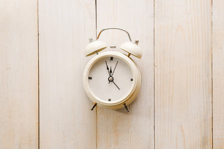 Alarm clock showing almost 12 o clock, on old white wooden floor background - Time concept.の写真素材