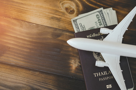 White model of passenger plane with passport and money on old wooden background. Travel saving and planning concept - Top view.の写真素材