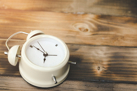Alarm clock showing almost 12 o clock, on old wooden floor background - Time concept.の写真素材