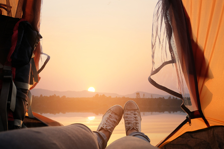 Feet of young women relaxing with lake view from tent camping entrance outdoor. Travel wanderlust lifestyle concept adventure vacations outdoor, Summer holiday and vacation tripの写真素材