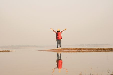 Tourist woman relaxing alone with a large backpack enjoying in lake view. Travel wanderlust lifestyle concept adventure vacations outdoor, Summer holiday and vacation tripの写真素材