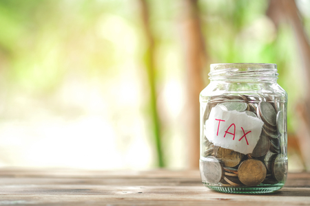 saving money with hand putting coins in jar glass, save and investment money for prepare in the future - saving financial conceptの写真素材