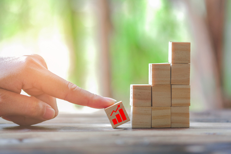 Wood block stacking as step stair and coins stacked, business growth to success.Startup concepts with business strategy symbols on wooden cubes - Risk management.の写真素材