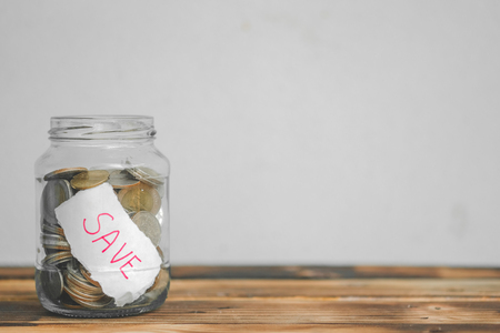 saving money with hand putting coins in jar glass, save and investment money for prepare in the future - saving financial conceptの写真素材