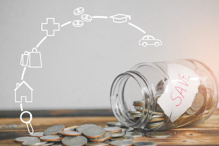 saving money with hand putting coins in jar glass with business strategy symbols, save and investment money for prepare in the future - saving financial conceptの写真素材
