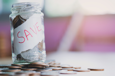 saving money with hand putting coins in jar glass, save and investment money for prepare in the future - saving financial conceptの写真素材