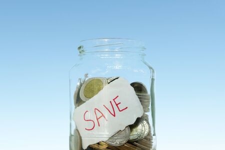 saving money with hand putting coins in jar glass, save and investment money for prepare in the future - saving financial conceptの写真素材