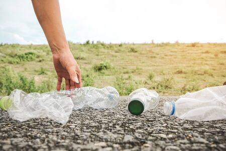 The volunteer picking up a bottle plastic in to a bin bag for cleaning, volunteering concept. Environmental pollution and Ecological problem.の写真素材