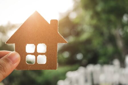 Hand holding Paper house model on bokeh background. Home loan for new family. Loan for real estate concept.の写真素材