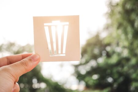 Hand holding recycling symbol created with paper cut and landscape on background, Concept of environmental conservation and protection.の写真素材