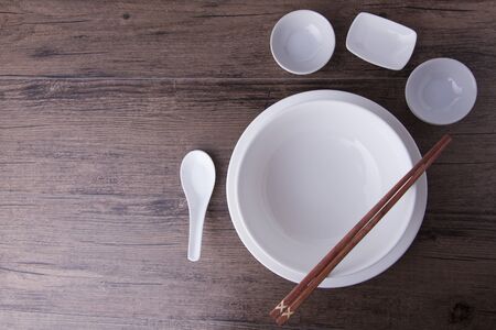 White bowl, spoon, sauce bowl and chopsticks on wood tableの写真素材
