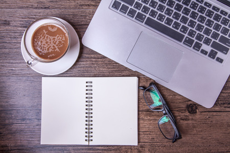 Computer, tea, glasses and notebook on wood tableの写真素材