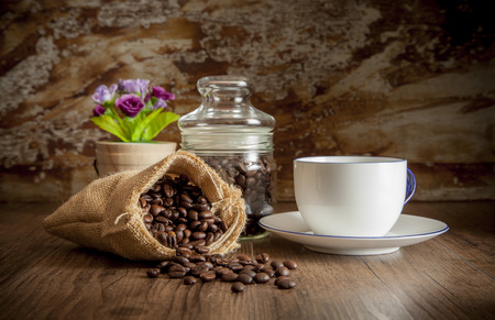 Coffee in sack and white cup, decorate with glass jar, flower and blur old wall for backgroundの写真素材