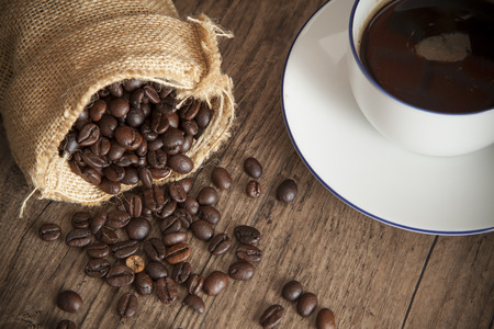 Roast coffee seed and Sweet and fragrant coffee in white cup on wood tableの写真素材