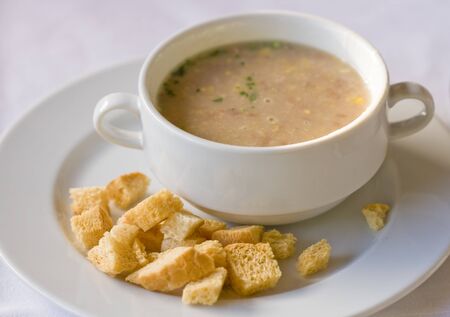Cream of soup served with dried crust and green. On white backgroundの写真素材