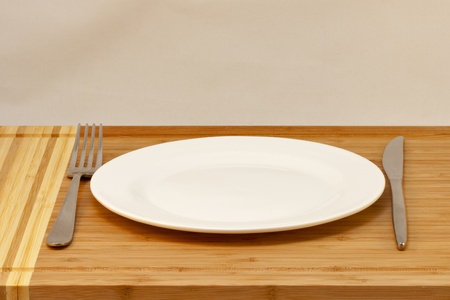 cutlery empty plate, table knife and fork on a wooden desk