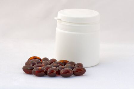 closed white bottle with brown capsules closeup against whiteの写真素材