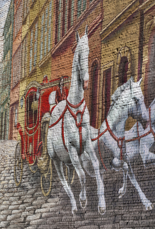 KIEV, UKRAINE - FEBRUARY 18, 2014: Unknown artist street graffiti on building brick wall with red coach and three white horses rushing on the street.のeditorial素材