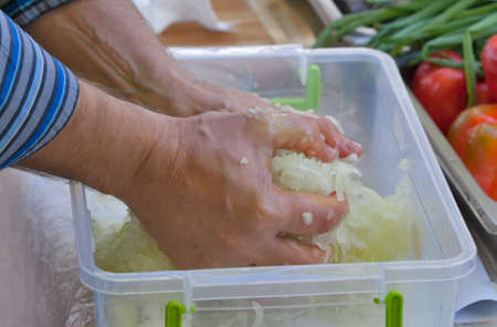 man hands knead the chopped onion closeupの写真素材