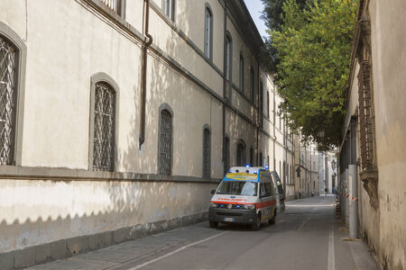 LUCCA, ITALY - SEPTEMBER 06, 2014: Unrecognizable people walk along the street with ambulance car in nursing home in Lucca, Italy.のeditorial素材