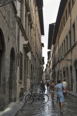 FLORENCE, ITALY - SEPTEMBER 10, 2014: Unrecognized pedestrians walk along city narrow street with parked bicycles. Florence is the administrative center of the region of Tuscany. Population of more than 373,000 people.のeditorial素材