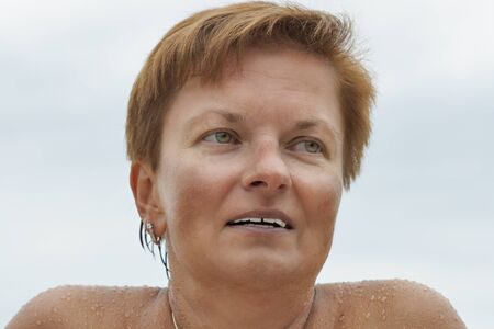 smiling middle aged caucasian tanned naked woman outdoor portrait after sea bathingの写真素材