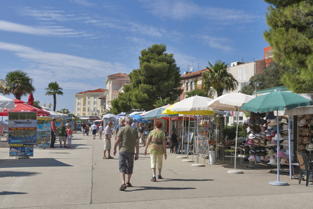 POREC, CROATIA - SEPTEMBER 14, 2014: Unrecognizable people walk along seafront with small shops. Porec almost 2,000 years old is a town and municipality on the western coast of the Istrian peninsula.のeditorial素材