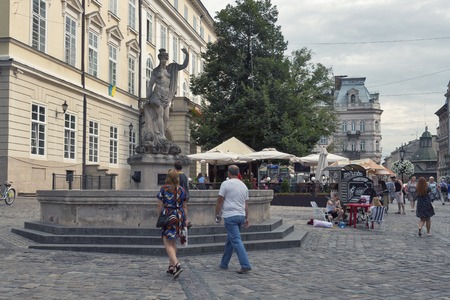 LVIV, UKRAINE - JULY 29, 2014: Pedestrians walk in front of ancient statue of Amphitrite on Market Rynok Square, the central square and most popular touristic place in historical part of old town.のeditorial素材