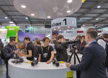KIEV, UKRAINE - OCTOBER 11, 2015: Visitors testing professional photographic cameras on Nikon booth during CEE 2015, the largest electronics trade show of Ukraine in ExpoPlaza Exhibition Center.のeditorial素材