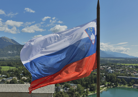 Slovenian national flag fluttering over Lake Bled and townの写真素材