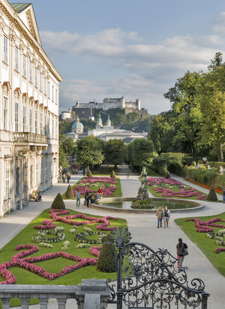 SALZBURG, AUSTRIA - SEPTEMBER 09, 2015: Unrecognized people walk in world famous Gardens of Mirabell with Fortress Hohensalzburg in the background. The Gardens were redesigned around 1690.のeditorial素材