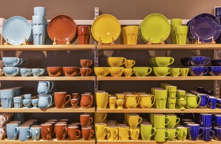 Retail display of multicolored porcelain dishes and mugs on the shelves.の写真素材