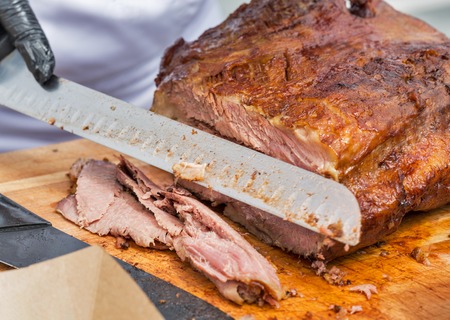 chief cutting thin sliced pastrami beef closeup on cutting boardの写真素材