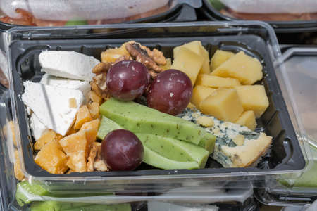 Street food cheese assortment plate with grapes and walnuts in box closeupの写真素材