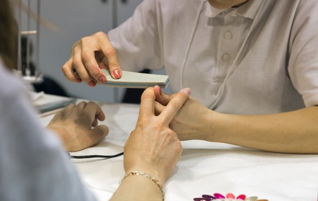 Manicurist master makes nail filing on woman hand closeup, selective focusの写真素材