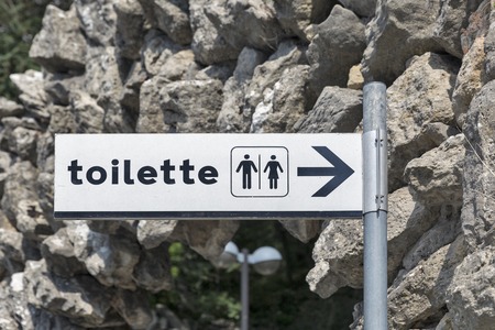 Toilet direction sign on white plate closeup outdoorの写真素材