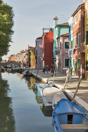 BURANO, ITALY - SEPTEMBER 22, 2016: People walk along canal between park and colorful street. Burano is an island known for its lace works and brightly colored homes which attract thousands tourists.のeditorial素材