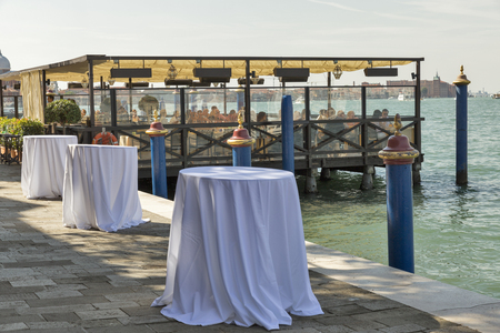 VENICE, ITALY - SEPTEMBER 23, 2016: Unrecognized people have a lunch in a restaurant on the shore of Guidecca island in Venice lagoon. Venice is situated across 117 islands separated by canals.のeditorial素材