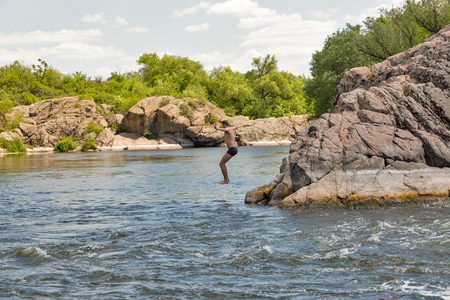 MIGEYA, UKRAINE - JUNE 01, 2017: Unrecognized young caucasian man jumps into the Southern Bug river close to famous Red Gate or Integral rapids.のeditorial素材
