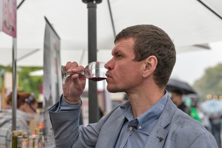 KIEV, UKRAINE - MAY 13, 2017: Unrecognized young man taste wine during Kyiv Food and Wine Festival in National Expocenter, a permanent multi-purpose exhibition complex in the Teremky neighborhood.のeditorial素材