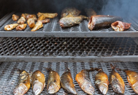 Smoked mackerel, salmon and chicken wings closeup outdoors in smokehouse, street foodの写真素材